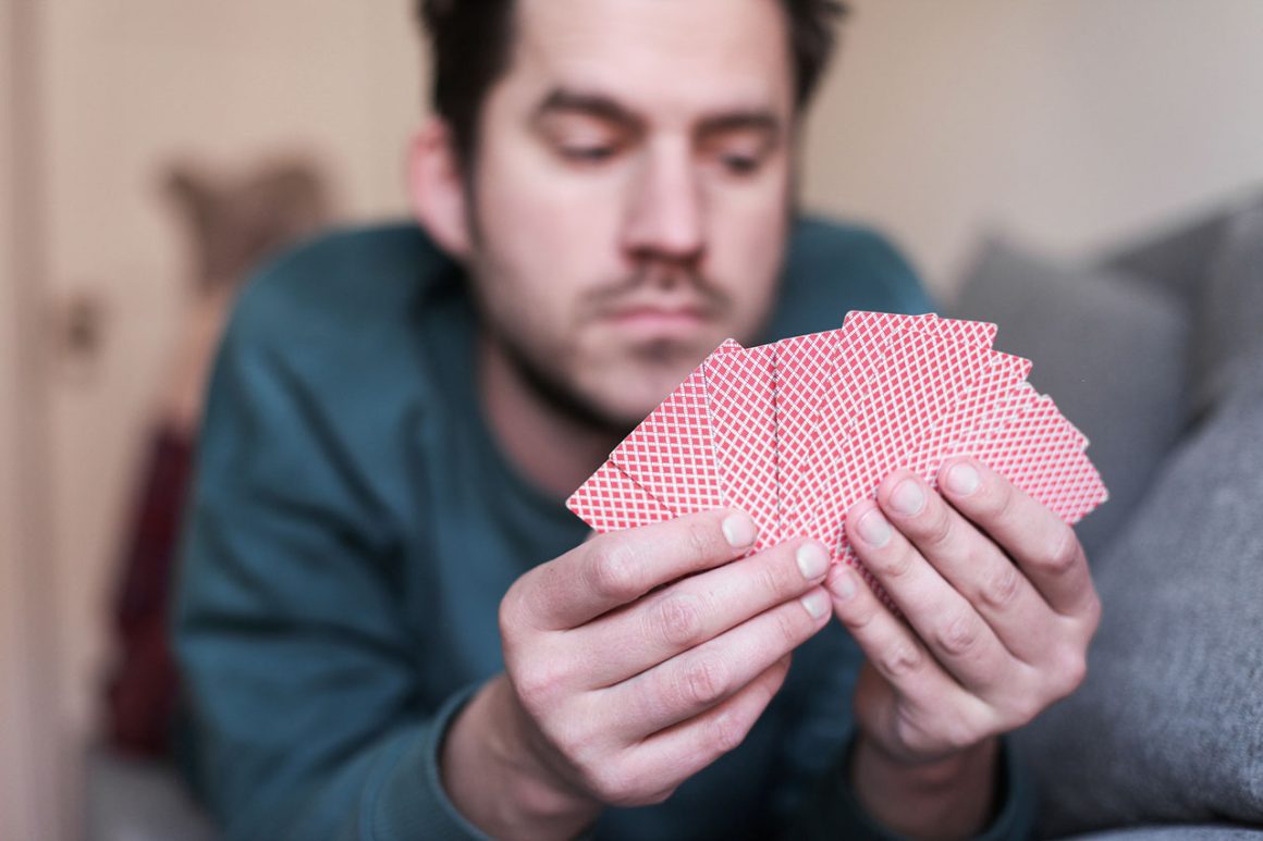 Man playing cards in front of a poker table.